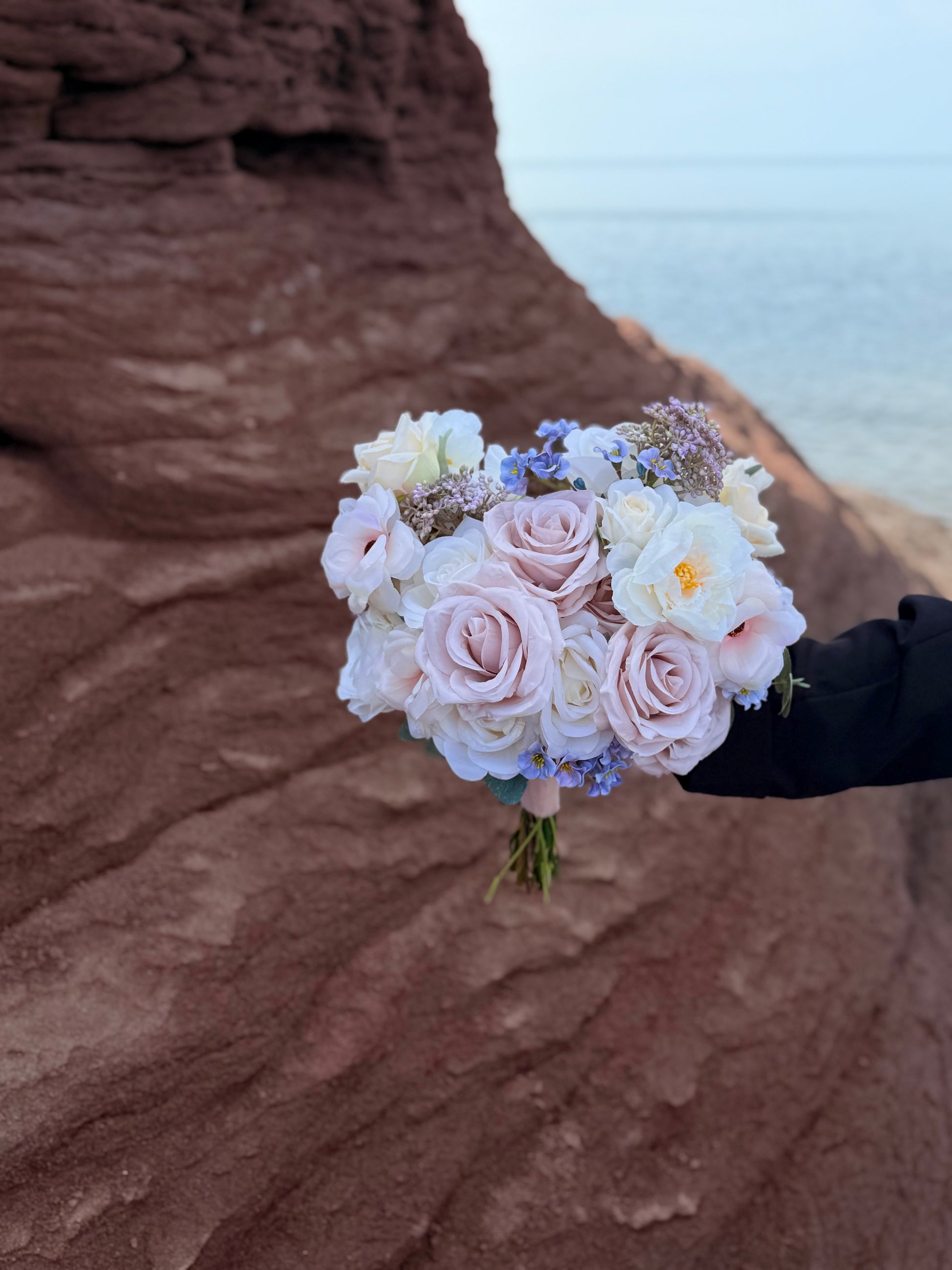 Pastel bridal bouquet with cream roses, garden roses and delicate blue accents. Classic and perfect